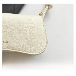Close-up of cream leather shoulder bag showing lychee grain texture and gold metal hardware