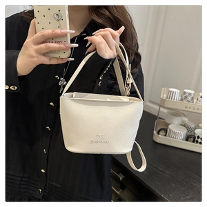 Detail view of the white pebble leather bucket bag featuring metal buckle and brand logo