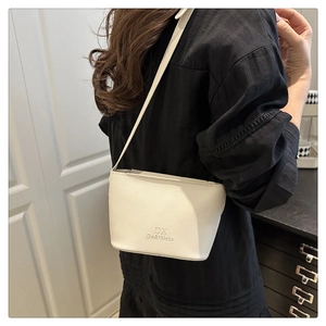 Close-up of white textured leather bucket bag with embossed logo on a female model