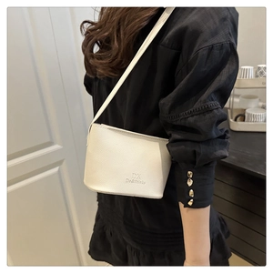 Detail of white lychee leather texture and embossed logo on minimalist bucket bag