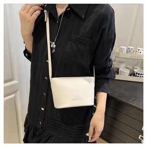 Detail of cream white crossbody bag in lychee pattern leather with embossed lettering
