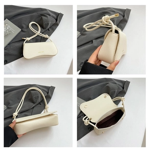 Detail view of cream-colored litchi grain leather bag with knotted shoulder strap