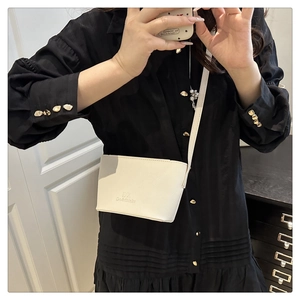 Close-up of a mini white bucket bag with DX logo shown in a lifestyle mirror selfie