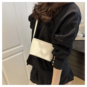 Detailed close-up of cream mini bucket bag with embossed logo on a black dress