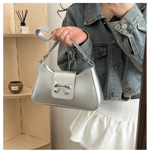 Silver PU leather shoulder bag with metallic bow detail shown styled with casual outfit