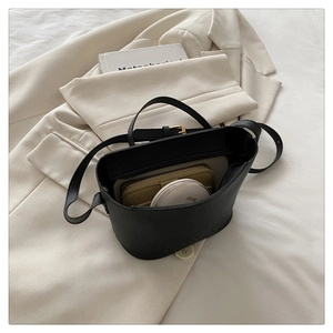 Inside view of black lychee grain bucket bag with a yellow wallet and cushion compact