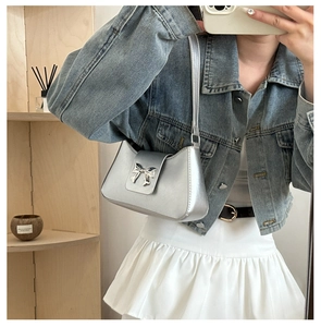 Close-up of a silver Y2K metallic shoulder bag with a metal bow buckle on a shelf
