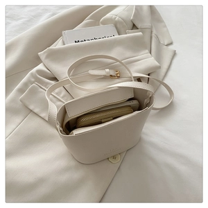 Close-up of cream leather bucket bag with pebble texture and matching interior wallet