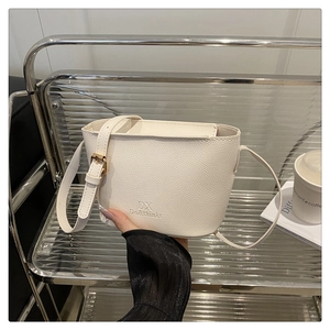 Close-up of white lychee pattern bucket bag with DX logo and gold hardware details