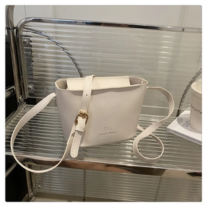 Detailed macro of white litchi pattern leather bucket bag with gold metal buckle hardware