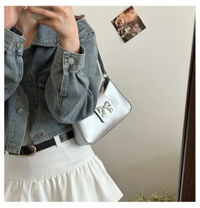 Mirror selfie showing a silver bow shoulder bag styled with a denim jacket and skirt