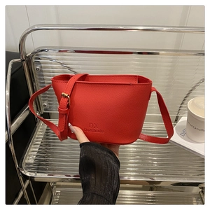 Close-up of red lychee pattern leather bucket bag with metallic logo and thin strap