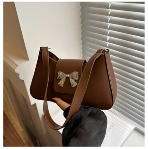 Detailed close-up of brown PU leather shoulder bag featuring a silver metal bow buckle