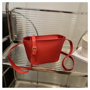 Detail of red pebbled leather bucket bag with gold buckle and embossed brand logo