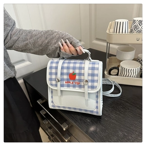 Detail of light blue gingham crossbody bag with apple embroidery and top handle
