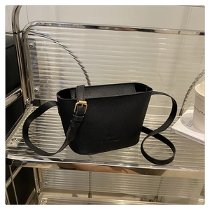 Detail of black lychee texture bucket bag with adjustable strap and gold buckle