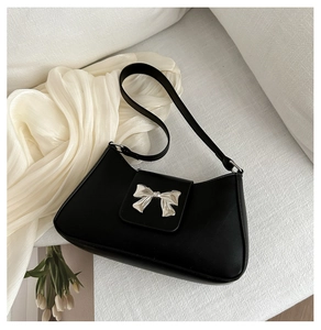 Close-up of black matte faux leather bag featuring a silver metal bow clasp decoration