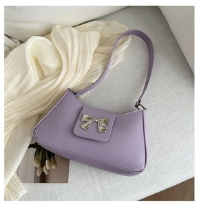 Detail of silver metal bow buckle on lavender faux leather shoulder bag with smooth texture
