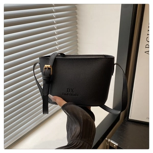 Detail of black lychee grain texture bucket bag with adjustable strap and gold buckle