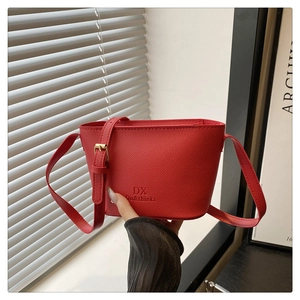 Close-up of red lychee pattern leather bucket bag featuring a gold buckle and embossed logo