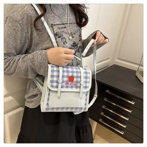 Detail of blue plaid mini backpack featuring red apple embroidery and adjustable straps