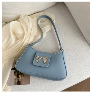 Detailed close-up of light blue leather bag featuring a silver metal bow buckle