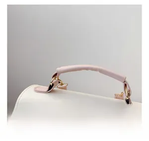 Détail d'un sac à main en cuir blanc avec poignées roses et attaches dorées