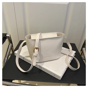 Detail of white litchi pattern bucket bag featuring DX brand logo and slim strap