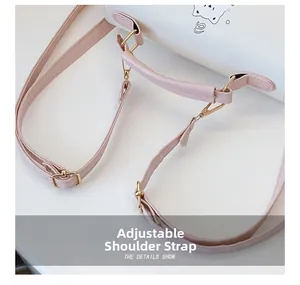 Détail de la bandoulière réglable en cuir rose avec boucle dorée sur sac blanc