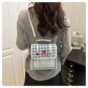 Close-up of mini blue plaid crossbody bag with embroidered apple and leather details