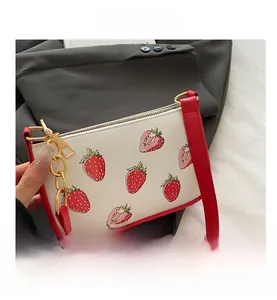 Top-down view of strawberry print PU leather handbag with red trim and gold hardware