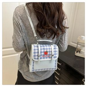 Detail of light blue gingham mini backpack with red apple embroidery and metal buckle