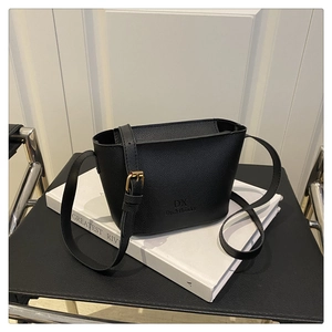 Detail of black pebbled leather bucket bag featuring a gold buckle and embossed brand logo