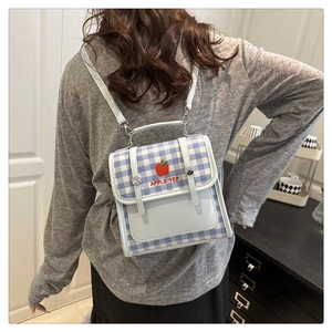 Detail of preppy light blue checkered mini backpack with red apple embroidery on a model