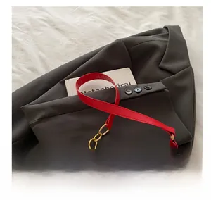 Close-up of white PU shoulder bag featuring strawberry patterns and red leather straps