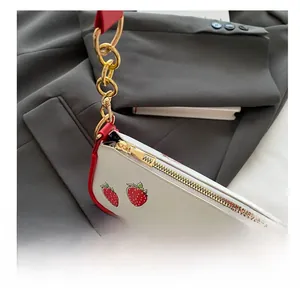 Detail showing the smooth golden zipper and metal chain strap on the strawberry print bag