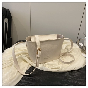 Close-up of beige lychee leather bucket bag with embossed logo and gold metal hardware