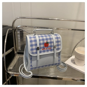 Dettaglio di un mini zaino a quadretti blu con ricamo su un supporto in metallo moderno