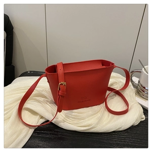 Detail of red bucket bag with lychee grain leather texture and gold hardware adjustments