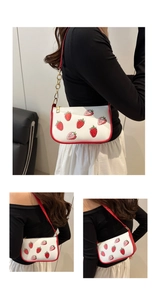 Detail of strawberry print shoulder bag with red piping and gold chain strap