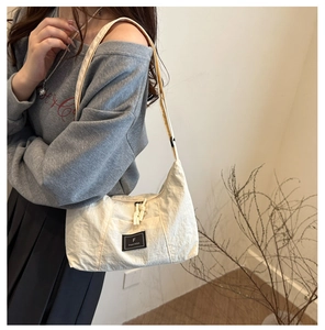 Detail of cream nylon hobo bag showing fabric texture, branded label, and shoulder strap