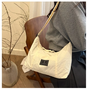 Detailed view of cream nylon crescent crossbody bag with adjustable wide shoulder strap