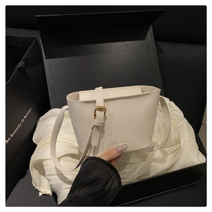 Close-up of white lychee leather bucket bag in a black gift box with satin lining