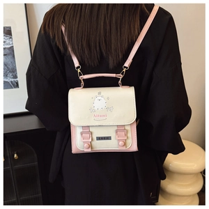 Detail view of pink and beige leather backpack featuring a cute cartoon hedgehog pattern