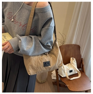 Detailed view of the khaki nylon tote bag featuring a brand label and wide shoulder strap