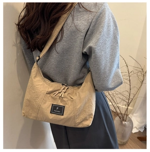 Close-up of khaki nylon crescent shoulder bag featuring the F FANYISSA logo patch