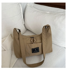 Detail of khaki nylon tote bag featuring brand logo, double zippers, and wide shoulder strap