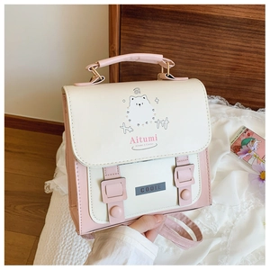 Close-up of a pink and white backpack featuring a cute puppy illustration and metal logo