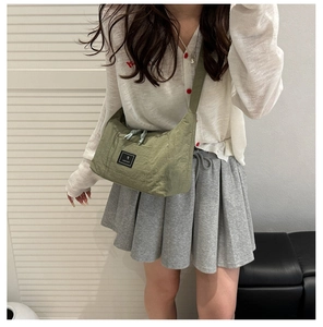 Close-up of green canvas shoulder bag showing nylon texture and black logo patch detail