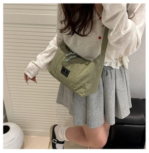 Detail of green nylon crescent shoulder bag with branded square patch and zip closure